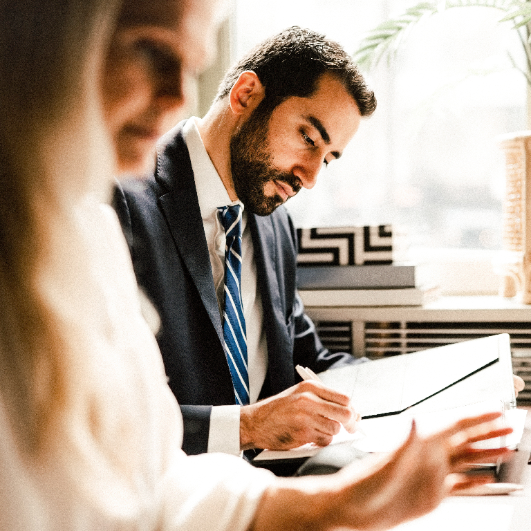 Professionals in business attire engaged in an icaew meeting with professionals, reviewing documents at a bright office table