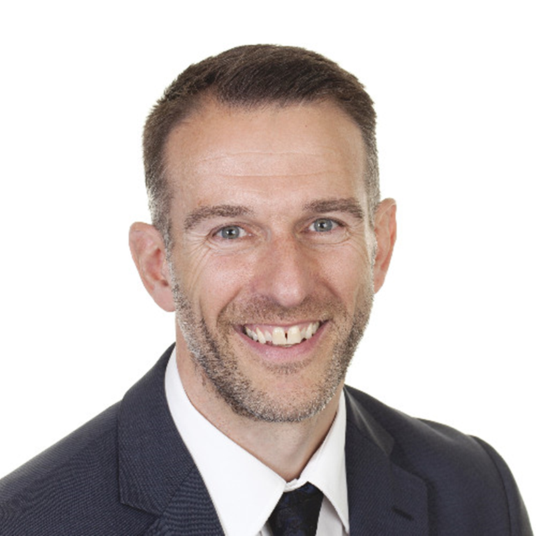 Robert Morris wearing a dark suit, white shirt and tie, posing against a white background.