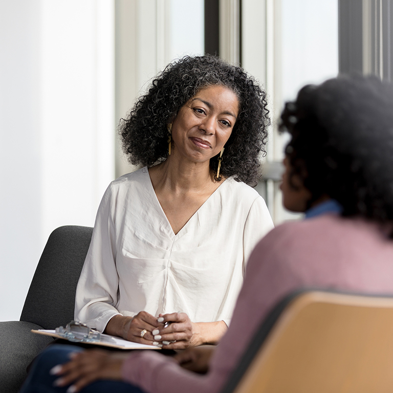 Two women engaged in a professional counseling session in a bright office, promoting communication and support for creating a stronger workplace.