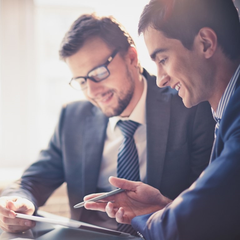 Colleagues in suits smiling and reviewing information on a tablet: underinsurance